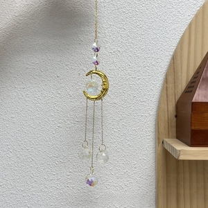 Detail of golden moon crystal suncatcher with iridescent faceted glass beads hanging on wall