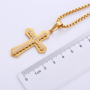 Mesure détaillée du pendentif croix en zircon doré à l'aide d'une règle en cm