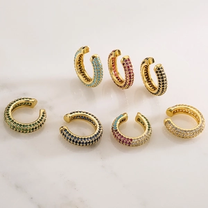 U-shaped gold plated ear cuffs set with colorful zircon stones on marble surface