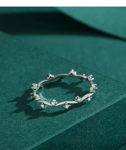 Macro view of wave-shaped S925 silver ring with zircon inlays on dark textured surface