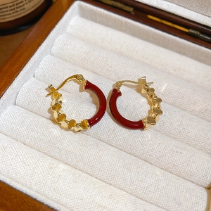 Détail de boucles d'oreilles cœur en émail rouge et doré sur écrin en velours blanc