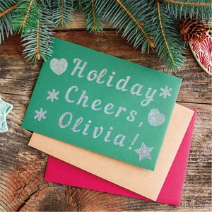 Close-up of glittery alphabet stickers on holiday greeting cards with envelopes on wood