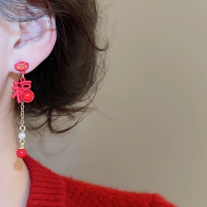 Detail of red tassel earrings featuring a Rich cloud stud and a lucky Fu character