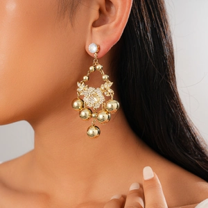 Elegant gold tassel earrings with sparkling crystals and metal spheres on a female model