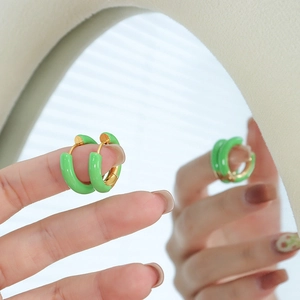 Green enamel gold-plated hoop earrings shown with mirror reflection in soft natural light