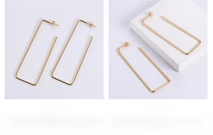 Macro view of large gold geometric rectangular earrings with minimalist thin wire frames
