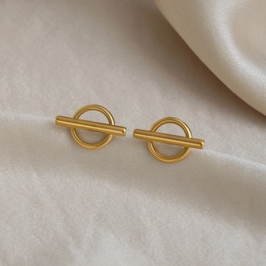 Detailed view of irregular 18K gold-plated stainless steel earrings on white silk fabric