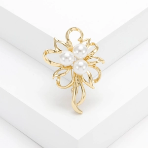 Elegant floral brooch featuring gold petals and three white pearls on a minimalist base