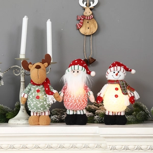 Leuchtende Weihnachtsfiguren mit Weihnachtsmann, Schneemann und Rentier auf einem Kaminims