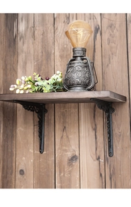 Close-up of vintage black cast iron bracket with ornate scrolling supporting a wooden shelf