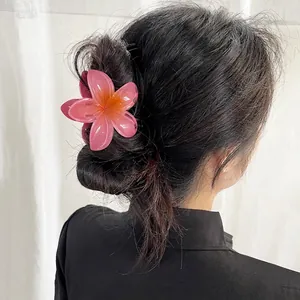 Tropical frangipani hair claw clip with pink and orange gradient petals in model hair