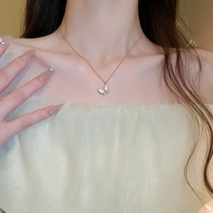 Close-up of rose gold butterfly pendant with white shell wings on woman's neckline