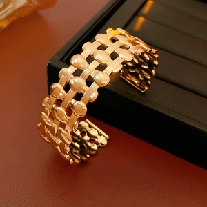 Detail of gold hollow triple-row woven texture open bangle with polished metal drops