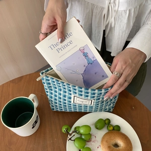 Placer un livre dans une pochette tissée à carreaux bleus avec fermeture éclair en métal