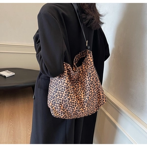 Back view of a large leopard print tote bag with black straps worn with a black coat