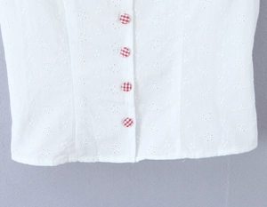 Dettaglio ricamo floreale bianco con bottoni a quadri rossi su camicia vestibilità slim
