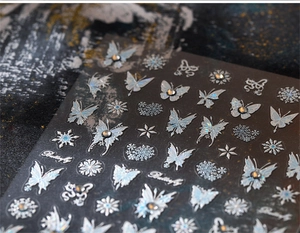 Detail of silver holographic butterfly and snowflake nail art stickers with metallic finish