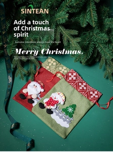 Close-up of burlap Christmas gift bags with Santa and Snowman embroidery on green background
