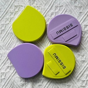Detail of soft purple and green makeup sponges with SISSIMU straps on woven fabric