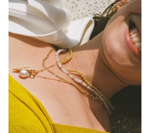 Detail of layered bohemian necklaces with golden shell, pearl, and colorful beads