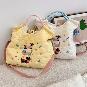 Detail of quilted tote bags featuring dog embroidery and colorful woven handles
