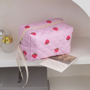 Detailed texture of quilted strawberry pattern makeup bag with soft ribbon pull