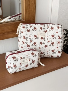 Floral corduroy makeup bag set with orange blossoms and quilted texture on a wooden shelf