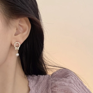 Detailed close-up of a 925 silver needle pearl bow earring worn by a model