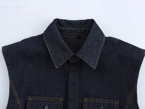 Détail d'un gilet en jean bleu foncé avec coutures contrastées et col pointu classique