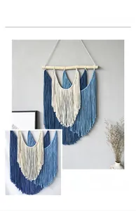 Détail de tenture murale en macramé tissé avec franges en coton bleu et beige sur bois