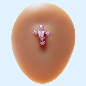 Detail of cross-shaped navel piercing with pink heart-shaped gems on silver base