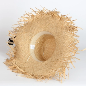 Close-up of a wide-brim raffia straw hat showing the frayed edges and woven texture