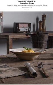 Detail of irregular handmade ceramic pasta bowl with rustic spiral texture on wooden table