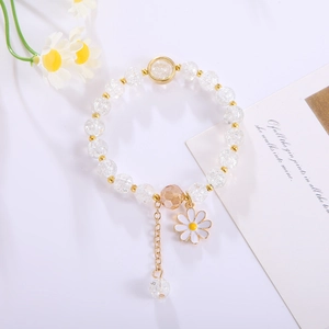 Detail of flower bracelet with crystal beads and daisy pendant on a white surface