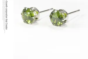 Detail view of olive green zircon stud earrings with silver claw setting and multifaceted cut
