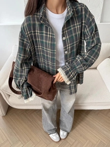 Close-up of green plaid shirt showing intricate lace cuffs and premium fabric texture