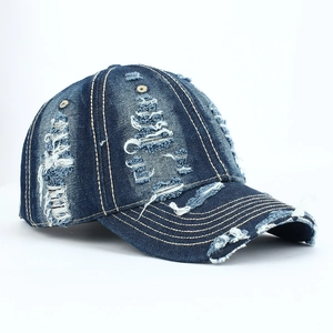 Close-up of distressed blue denim baseball cap with frayed edges and yellow stitching