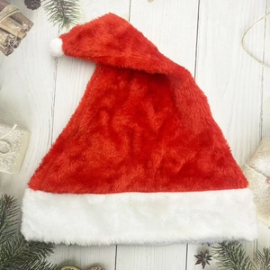 Flat lay of a plush red and white Christmas hat on a wooden background with festive decor