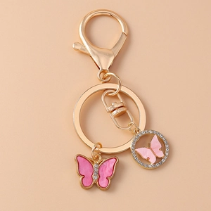 Detailed close-up of gold rhinestone butterfly keychain with pink enamel charms for bags