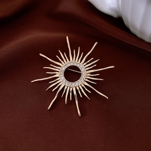 Macro detail of vintage gold plated sunburst brooch with pavé zircon on silk fabric