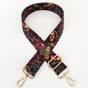 Detail of adjustable colorful patterned fabric bag strap with golden metal lobster clasps