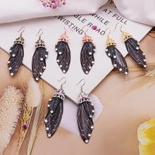 Macro detail of insect wing earrings with crystal caps in gold and silver finishes