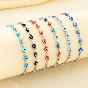 Adjustable stainless steel evil eye bracelets with colorful charms on fabric background