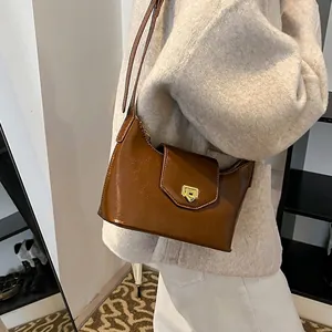 Brown faux leather baguette shoulder bag with gold clasp shown on a model