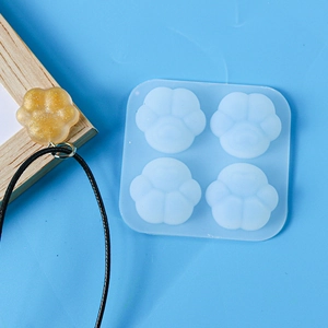 Detail of translucent cat paw silicone mold with finished gold glitter resin pendant