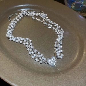 Macro detail of multi-strand pearl necklace featuring a diamond-encrusted heart pendant