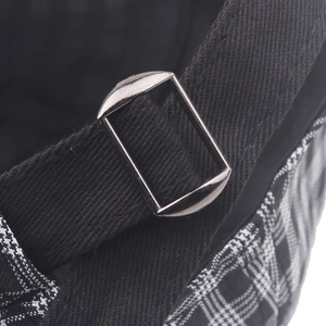 Detailed close-up of a gunmetal adjustable buckle on a vintage checkered newsboy hat