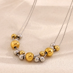 Detail of 18K gold and silver plated double-layer chain with alternating beads on sand