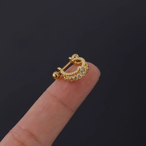 Detail of a 20G gold-plated double hoop tragus earring with cubic zirconia on a fingertip