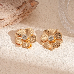Détail macro de boucles d'oreilles fleur dorées avec cristal sur fond de pierre